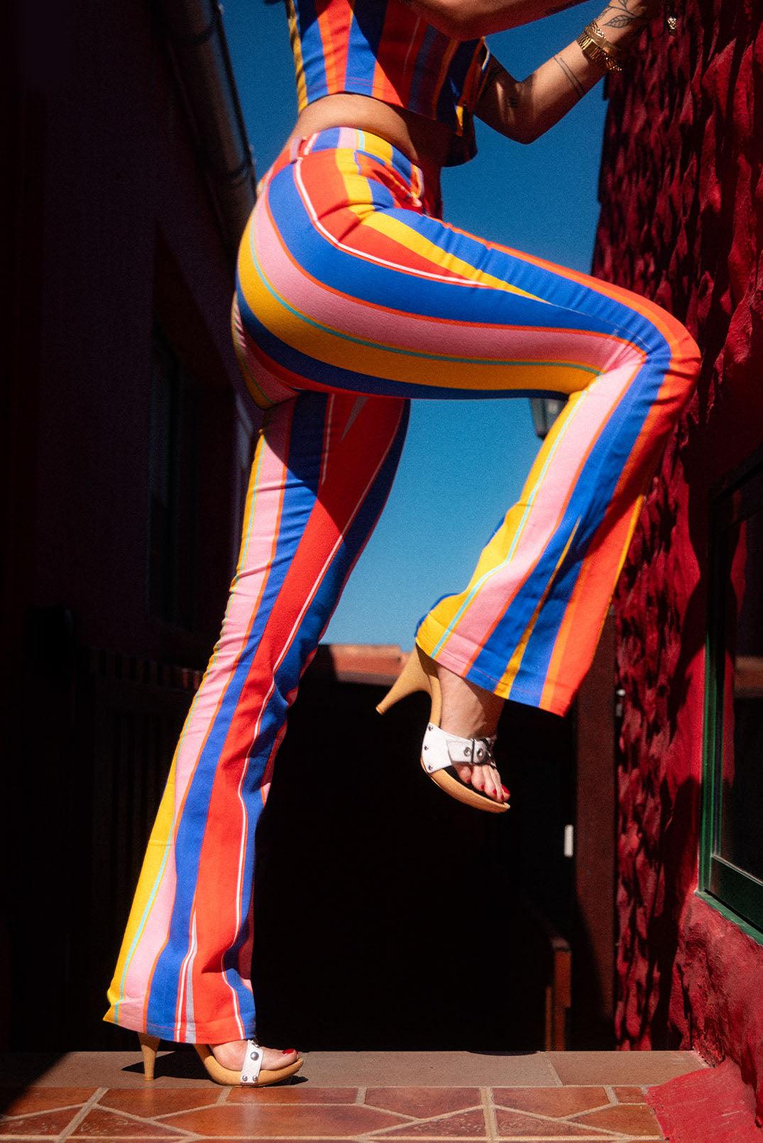 legs of girl in candy primary coloured vertical striped bootleg trousers in sun